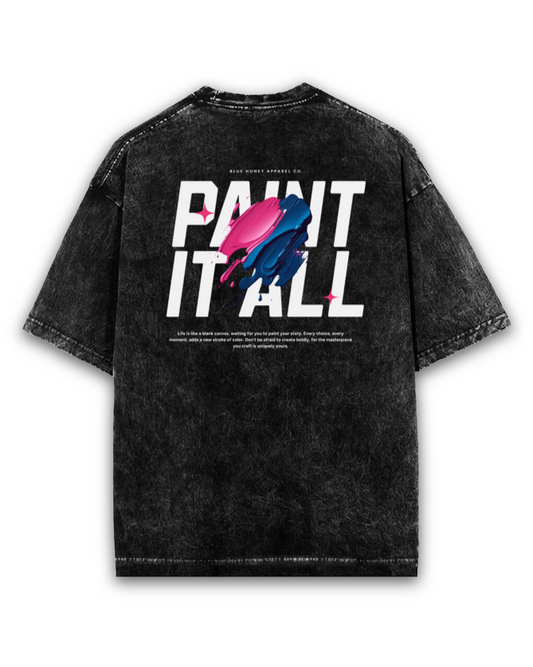 Back view of a black acid wash unisex t-shirt with bold white text reading “PAINT IT ALL,” partially overlaid by vibrant pink and blue paint-stroke graphics. Below the text is a motivational quote in small print. The t-shirt has a relaxed, oversized fit and features visible stitching for a vintage streetwear look.
