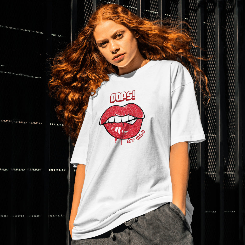 A female model standing wearing 'Oops My Bad' graphic oversized tshirt in white