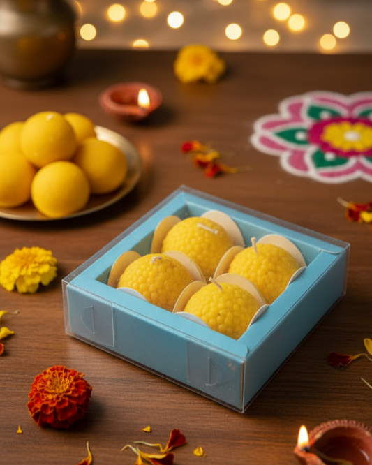 Yellow spherical candles in a blue box on a wooden surface with Diwali decorations.