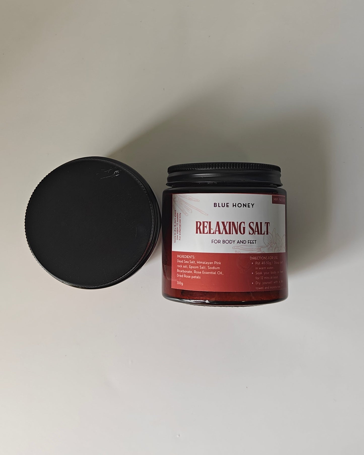 Jar of relaxing salt with a black lid on a white background