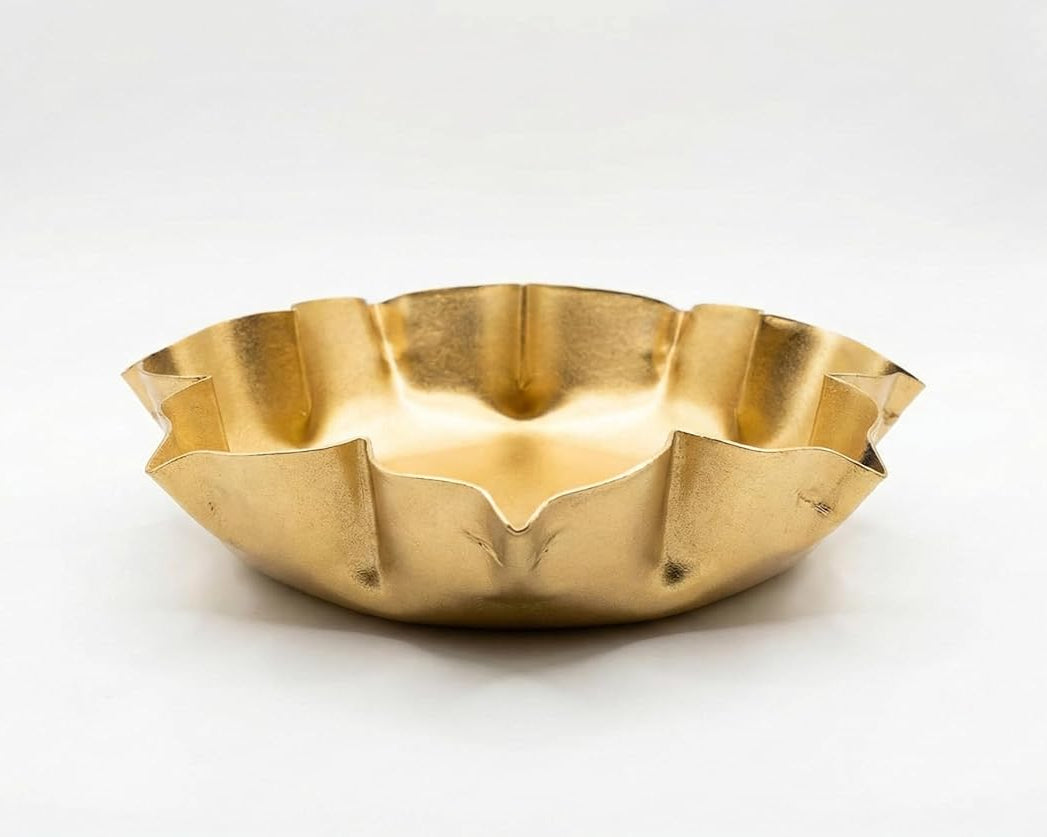 A gold-tone lotus-shaped urli bowl with a ruffled edge, presented from a front-facing perspective.