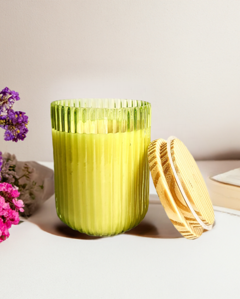 Green ribbed U-shaped glass jar candle with wooden lid.