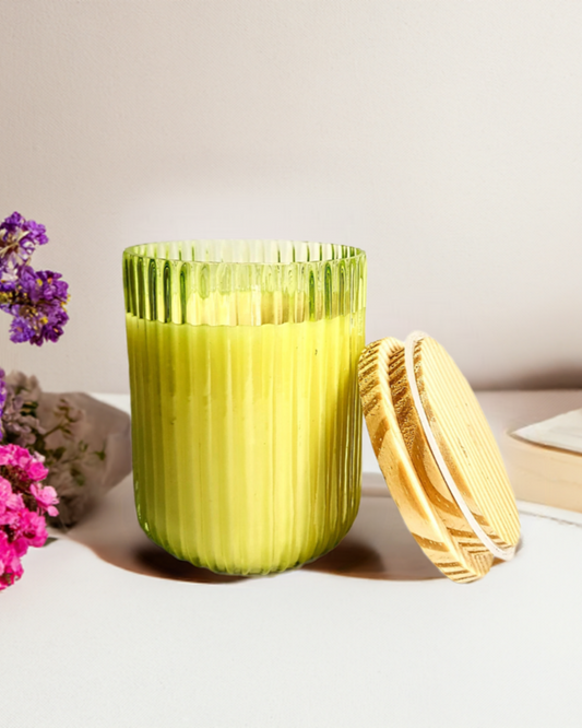 Green ribbed U-shaped glass jar candle with wooden lid.