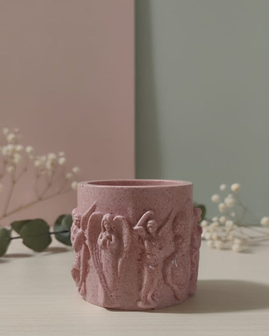 Pink ceramic candle jar with decorative embossing on a light surface with a neutral background