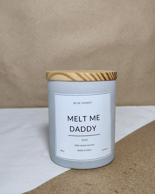 White matte glass candle jar with wooden lid label reads "Melt me daddy"