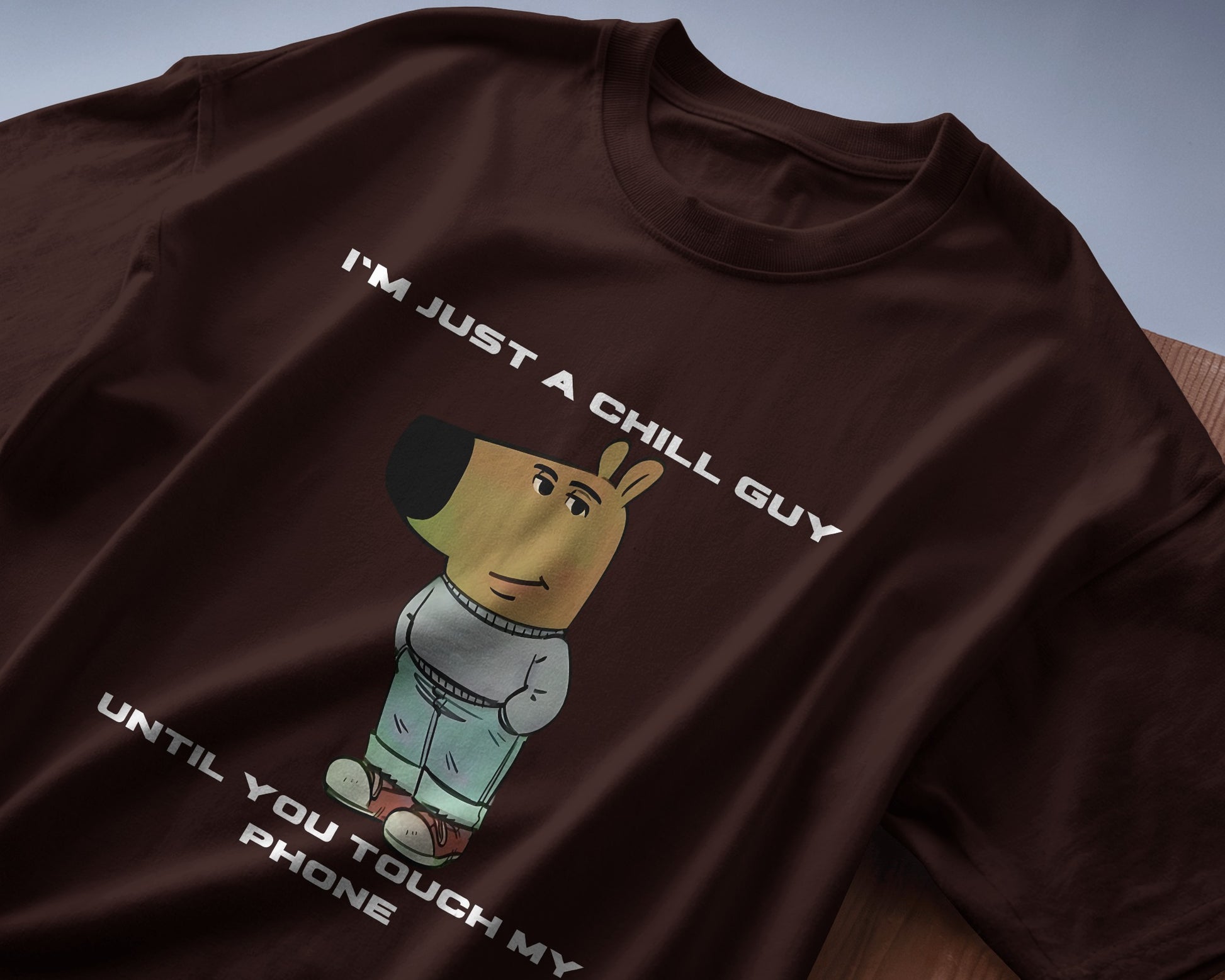 coffee brown "I’m Just a Chill Guy… Until You Touch My Phone" tshirt laying on the table