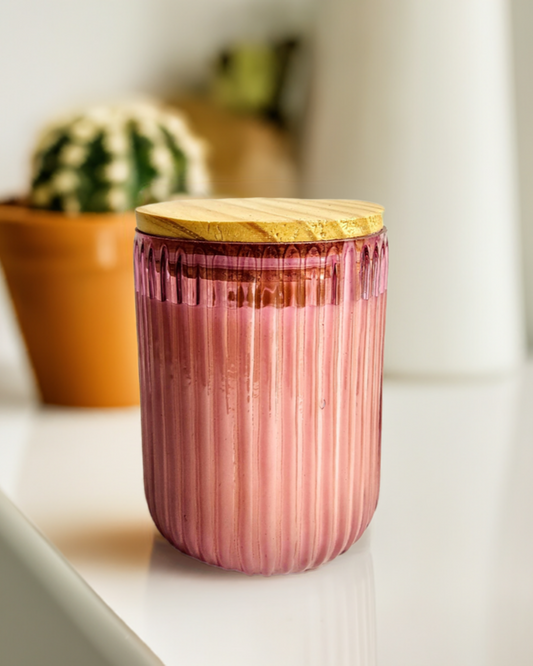 Pink ribbed U-shaped glass jar candle with wooden lid.