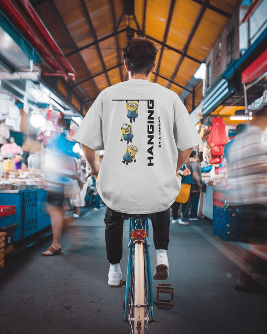 back view of a male model on a bicycle wearing an oversized white Minions tshirt