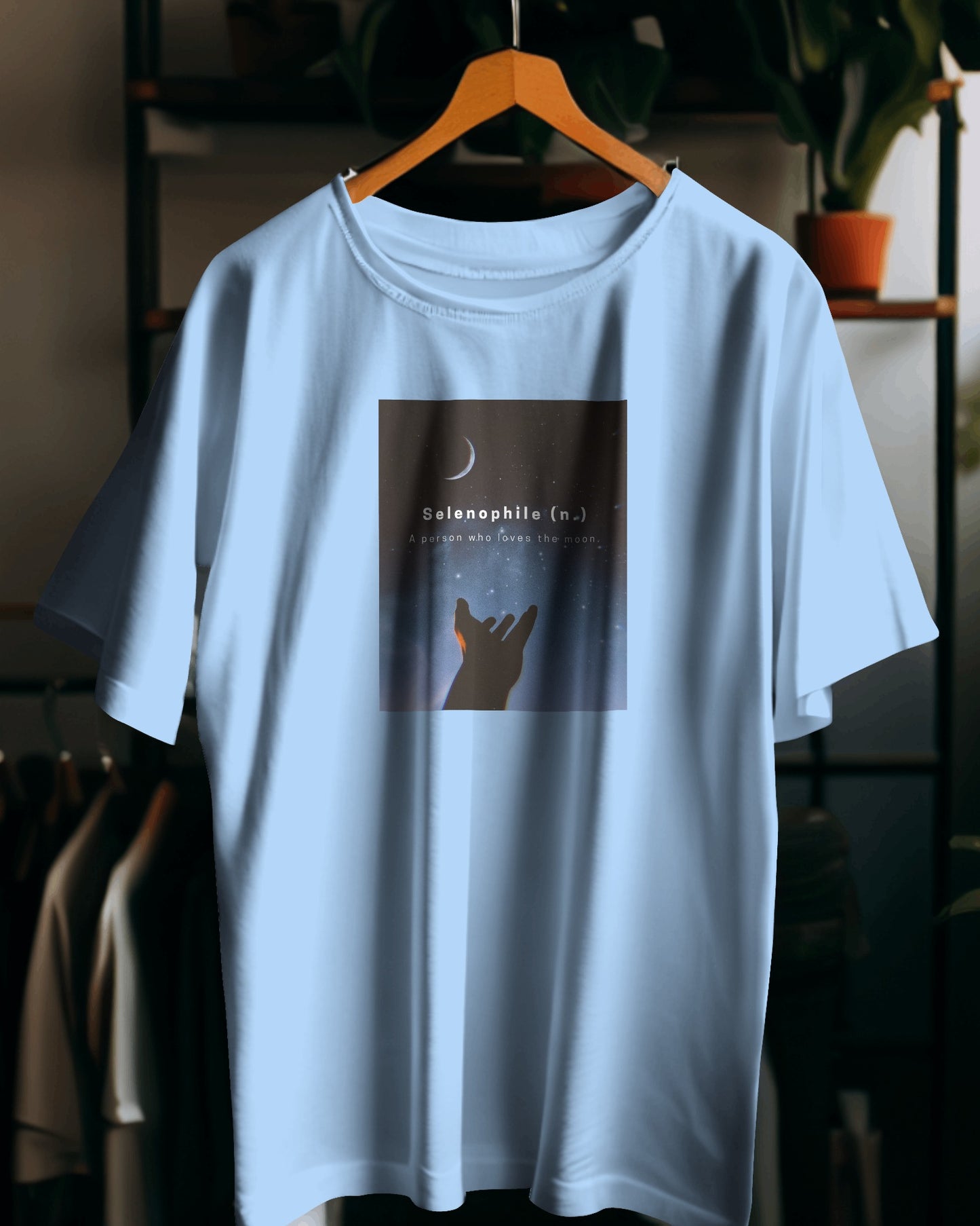 an oversized baby blue Selenophile tshirt on a hanger with a nice background of a bedroom