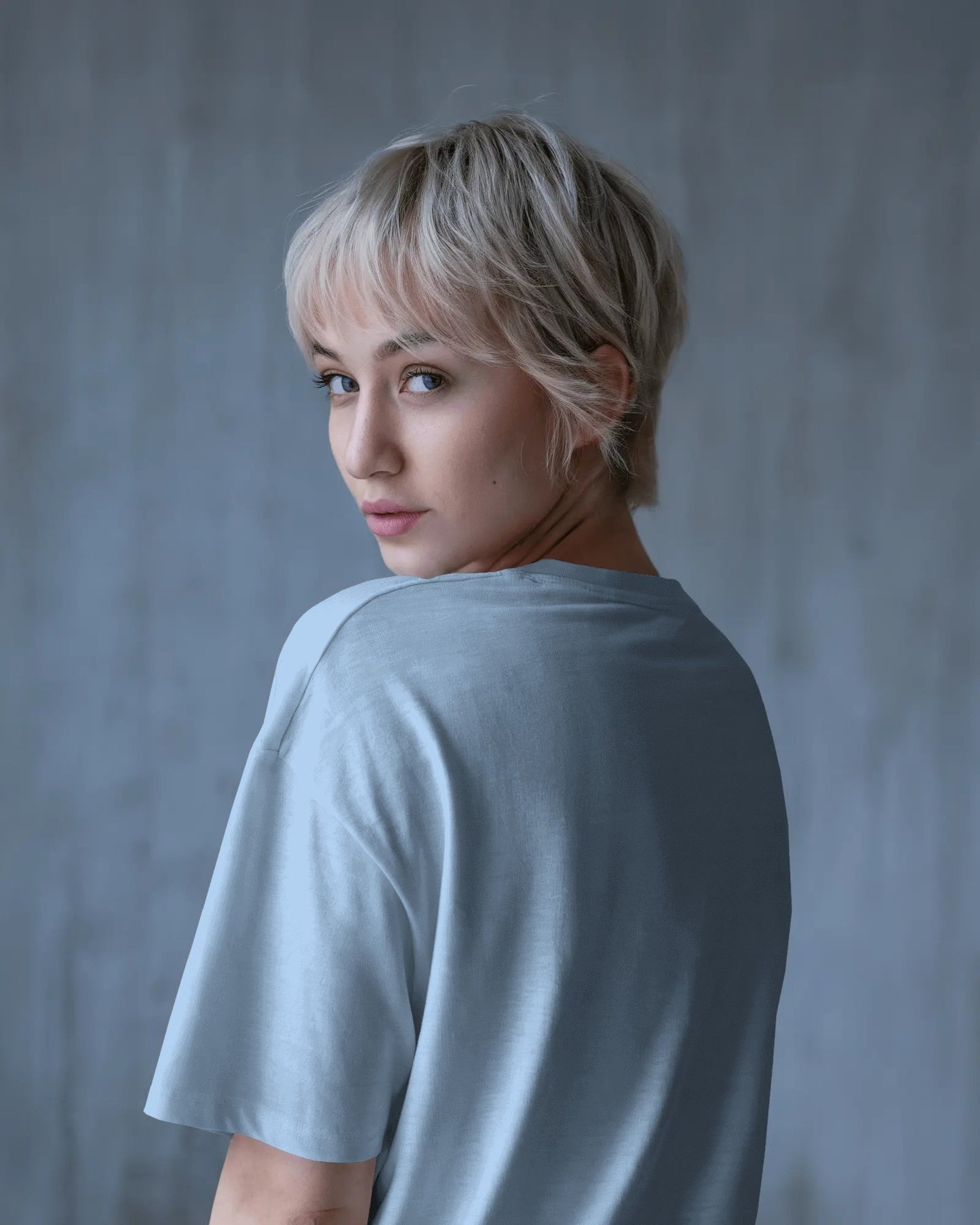 an Asian female model with blone hair showing the back of the baby blue Selenophile oversized tshirt