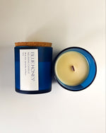Blue Honey relaxing candle in a frosted blue glass jar with a cork lid, viewed from above.