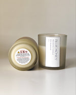 Close-up of a frosted soy wax candle with a label showing 'Blue Honey Relaxing Candle With Sandalwood'.