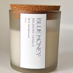 Frosted glass jar candle with a cork lid, labeled 'Blue Honey Relaxing Candle with Sandalwood'.