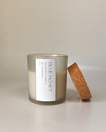 Frosted glass jar candle with cork lid, featuring a 'Blue Honey' label with sandalwood scent.