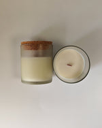 Frosted glass soy wax candle with a cork lid, showing the top view of the creamy white wax and wooden wick.