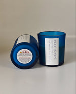 Close-up detail of a blue frosted soy wax candle with a white label showing 'BLUE HONEY' and scent notes.