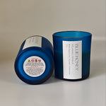 Close-up detail of a blue frosted soy wax candle with a white label showing 'BLUE HONEY' and scent notes.