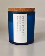 Blue Honey relaxing candle in a frosted blue jar with a cork lid, featuring lily, lavender, and rose scents.