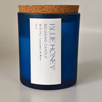 Blue Honey relaxing candle in a frosted blue jar with a cork lid, featuring lily, lavender, and rose scents.