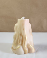 A 3D wave white soy wax pillar candle with gold accents, standing on a white surface.