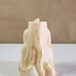 A 3D wave white soy wax pillar candle with gold accents, standing on a white surface.