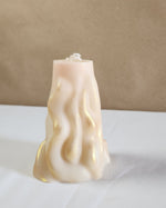 A 4" x 9.5" white soy wax pillar candle with a 3D wave design and gold accents.