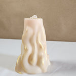 A 4" x 9.5" white soy wax pillar candle with a 3D wave design and gold accents.