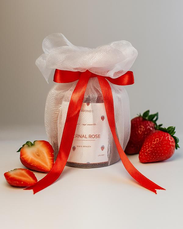 Eternal Rose scented soy wax candle gift-wrapped with red ribbon and strawberries, front view.
