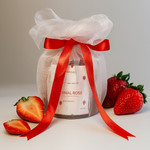Eternal Rose scented soy wax candle gift-wrapped with red ribbon and strawberries, front view.