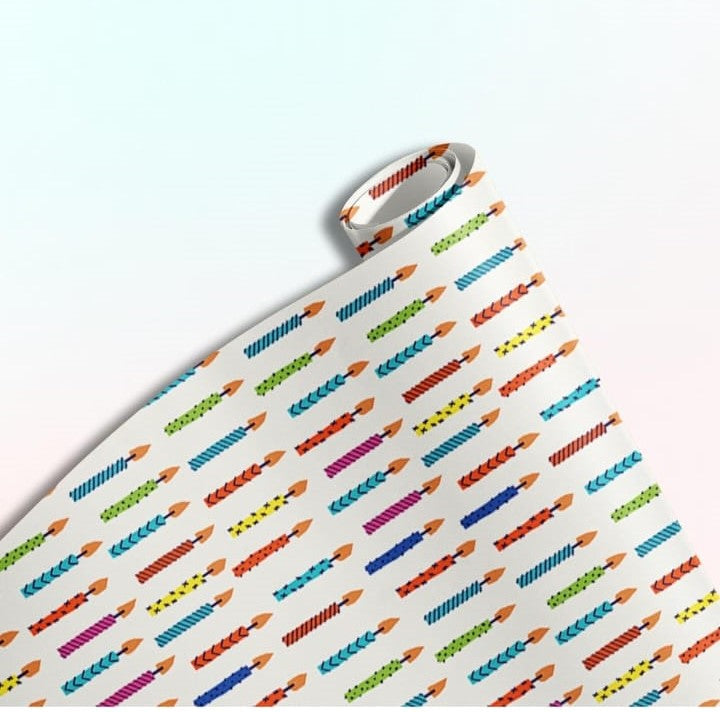 Rolled gift wrap featuring a repeating pattern of colorful birthday candles on a white background.