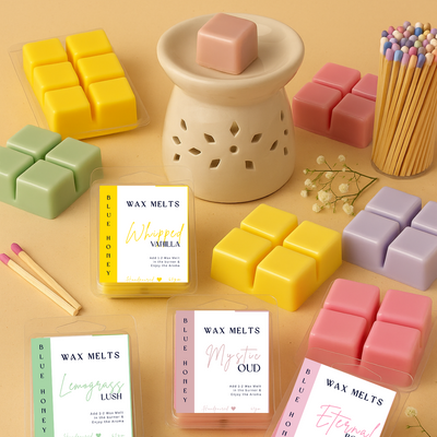 Blue Honey handcrafted wax melts in various colors and scents, displayed with a burner and matches.