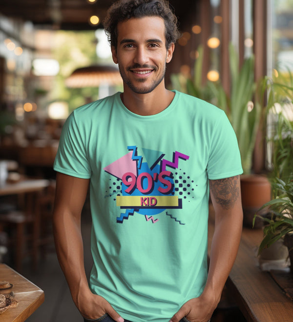 A smiling man wears a mint green '90s Kid' t-shirt in a lifestyle setting.