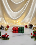 Two mini bubble soy wax candles, one red and one green, displayed on a marble surface with Christmas decorations.