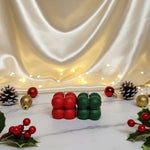 Two mini bubble soy wax candles, one red and one green, displayed on a marble surface with Christmas decorations.