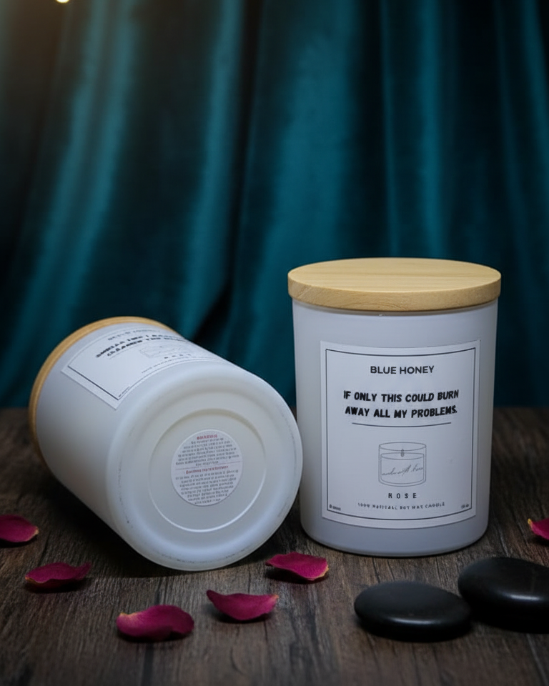 Two candles with wooden lids on a wooden surface with a dark curtain background