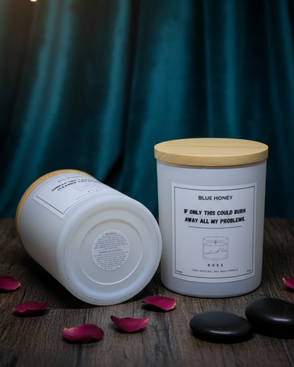 Two candles with wooden lids on a wooden surface with a dark curtain background