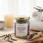 Blue Honey Lavender Relaxing Salt in a glass jar with a wooden scoop and lavender sprigs.