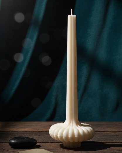 Tall white candle in a decorative holder on a wooden surface with a dark curtain background