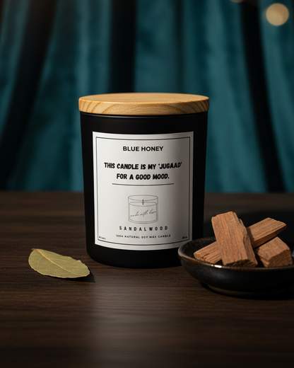 Candle with wooden lid on a dark surface with a blurred green curtain background