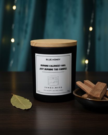 Candle with a wooden lid on a dark surface with a blurred background