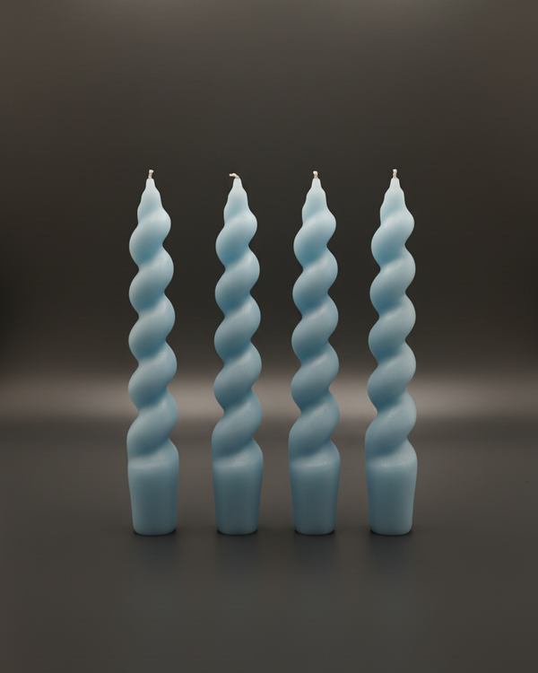 Set of four light blue spiral taper candles standing upright on a dark surface, front view.