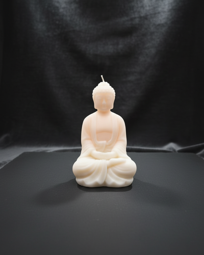 Candle shaped like a meditating Buddha figure on a black background