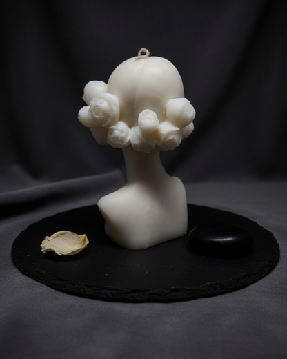 White sculpture of a bust on a dark surface with a black background