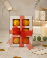 A gift box of four Motichoor Laddoo floating candles tied with a red ribbon, perfect for Diwali gifting.