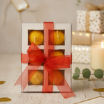 A gift box of four Motichoor Laddoo floating candles tied with a red ribbon, perfect for Diwali gifting.