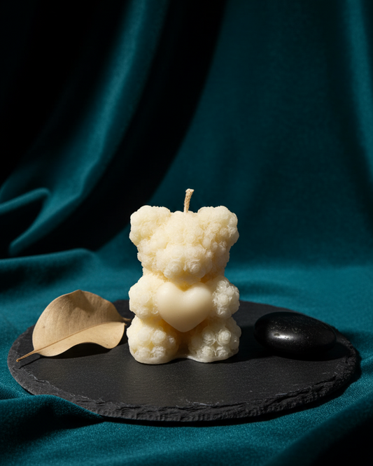 White bear-shaped candle on a black slate with a teal fabric background