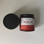Blue Honey Relaxing Salt for Body and Feet in a glass jar with a black lid, featuring Dead Sea salt and rose petals.