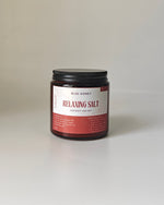 Blue Honey Relaxing Salt for Body and Feet in a glass jar with a black lid, featuring rose petals.