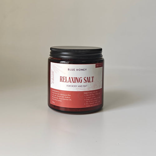 Blue Honey Relaxing Salt for Body and Feet in a glass jar with a black lid, featuring rose petals.