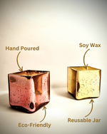 Two scented cuboid-shaped glass jar candles, one gold and one rose gold, with labels indicating hand-poured, soy wax, and reusable jar.